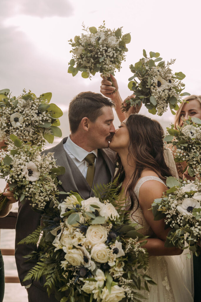 bride and groom kissing framed by bridesmaid bouquets