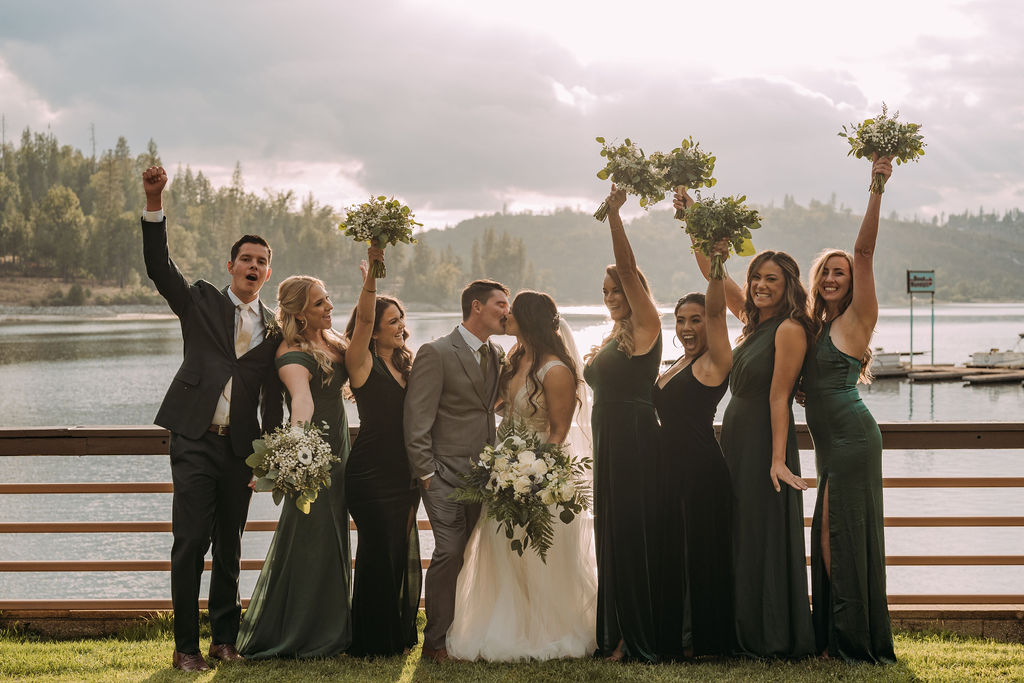 bride and groom kissing surrounded by their wedding party