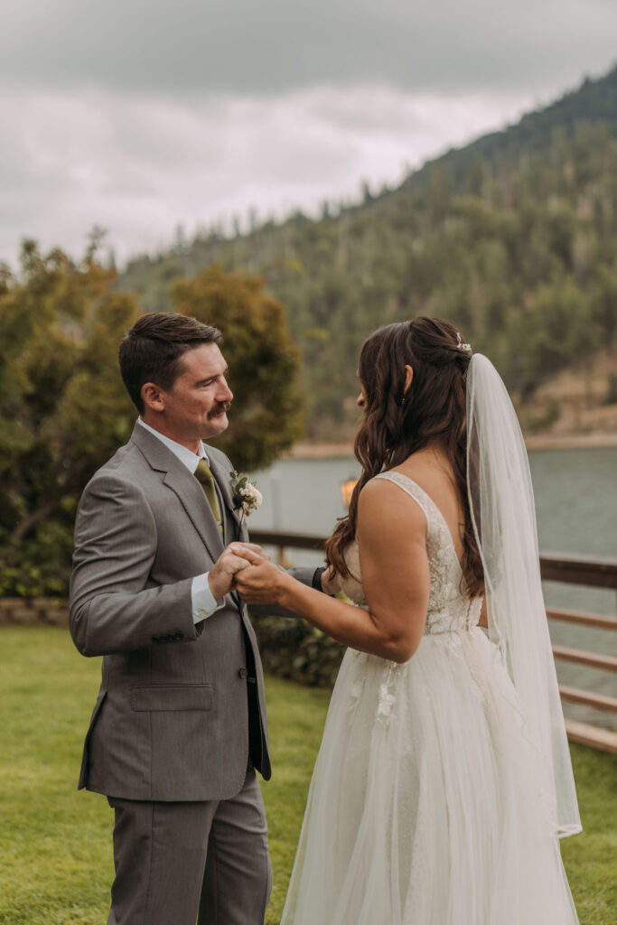 bride and groom first look with lake and forest views